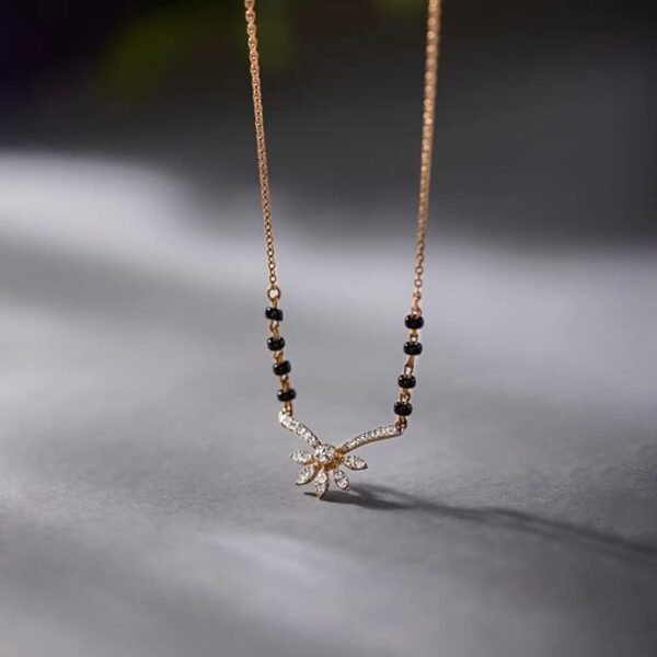 "Traditional black beaded mangalsutra with gold pendant featuring floral design on white background"